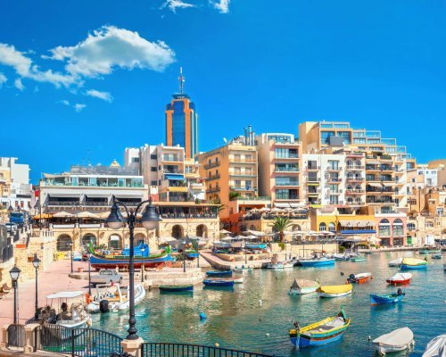 Waterfront of Spinola bay with colorful fishing boats at sunny day. St Julian's, Malta