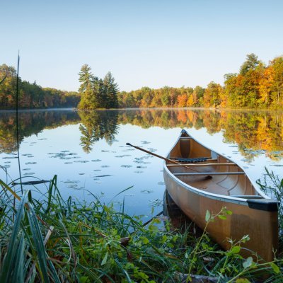 Canoe with paddle on shore of beautiful lake with island in northern Minnesota at sunrise